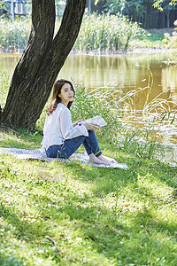 坐在公园草坪上放松的女青年图片