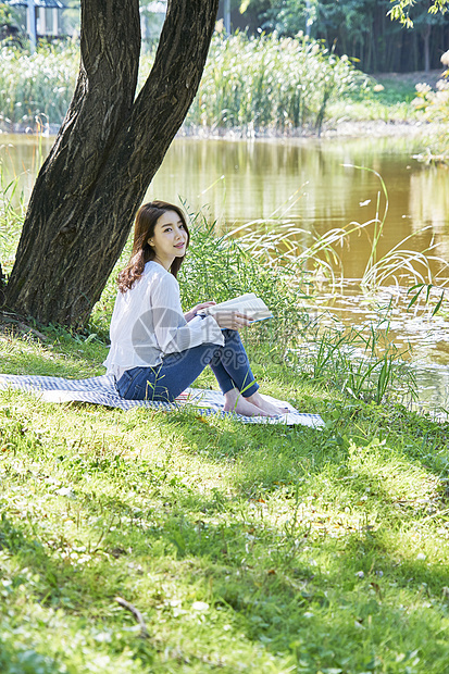 坐在公园草坪上放松的女青年图片