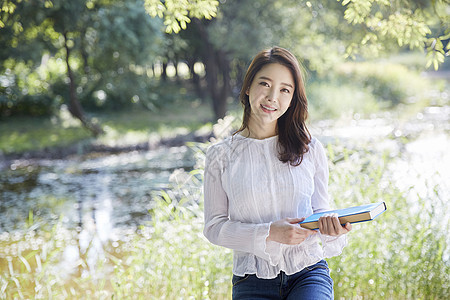 公园里拿着书的年轻女大学生图片