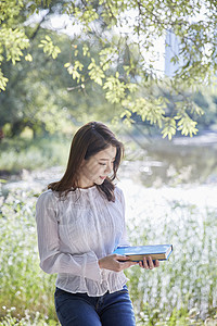 公园里拿着书的女大学生图片