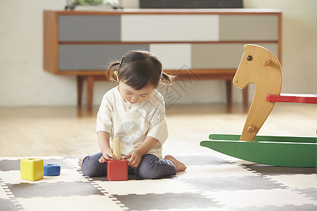 坐在垫子上玩积木的小女孩背景图片