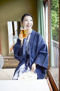 和服美女坐在窗边饮用的啤酒图片