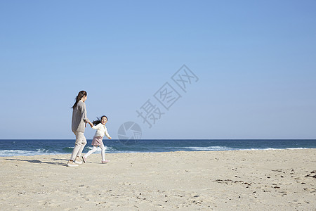 假期海边的母女旅行牵手奔跑图片