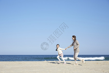 假期海边的母女旅行牵手奔跑图片