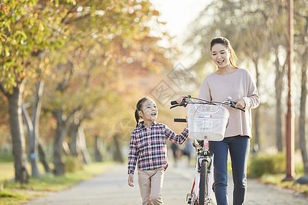 母女推行双人自行车游览公园图片