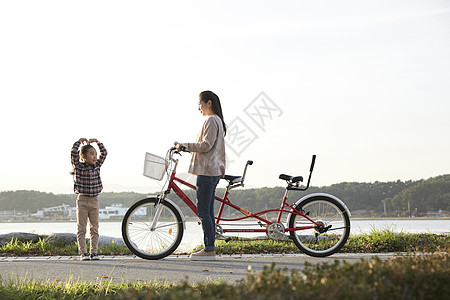 母女推行双人自行车游览公园背景