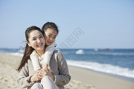 海边沙滩上在妈妈背上的女孩图片