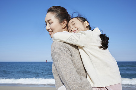 海边沙滩上的母亲背着女儿图片