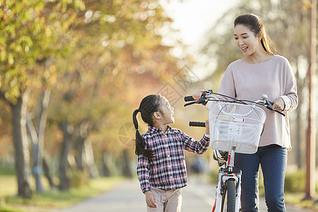 母女推行双人自行车游览公园图片