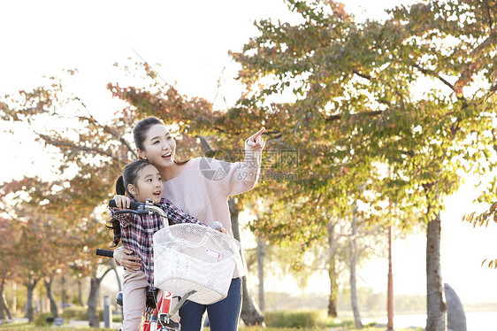 母亲带着女儿骑公园自行车游玩图片