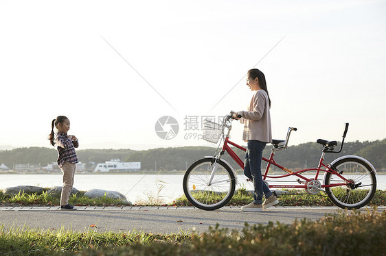母亲带着女儿骑公园自行车游玩图片