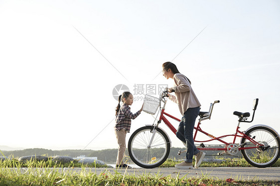 母亲带着女儿骑公园自行车游玩图片