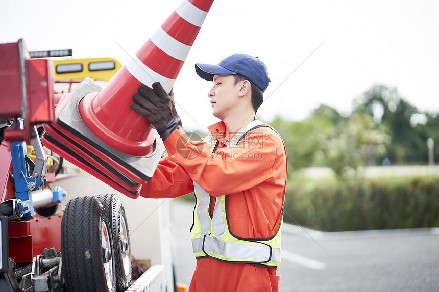 搬运放置路障锥桶的道路救援服务人员图片