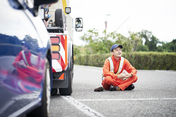 盘腿坐在地上的道路救援服务人员图片