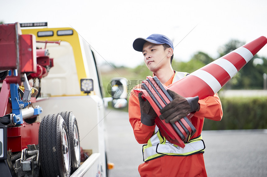 搬运路障锥桶的道路救援服务人员图片