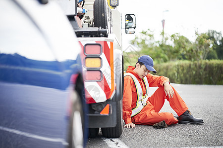 靠着车辆休息的道路救援服务人员图片