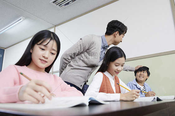 老师在教室里指导学生写作业图片