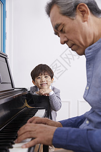 男孩看着爷爷弹奏钢琴图片
