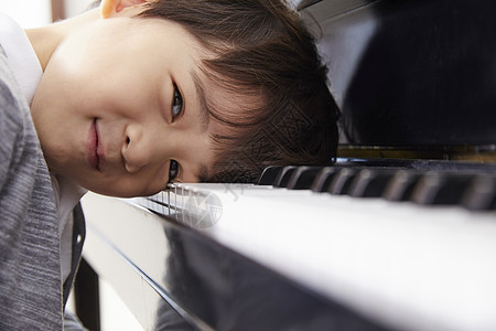 男孩趴在钢琴上嬉笑图片