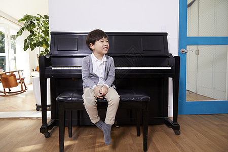 室内男孩在钢琴前坐着嬉笑图片