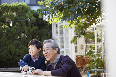 60年代玩耍庭院里玩耍的祖孙两背景