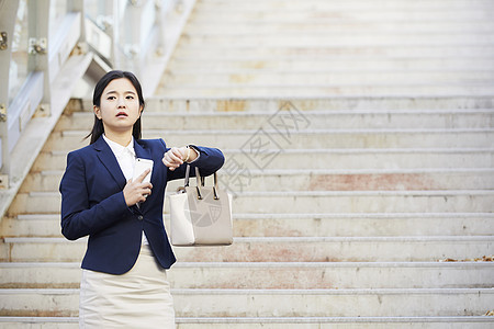 拿着手提包看时间担心的年轻女子图片