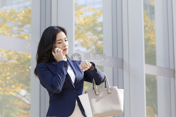 接电话看着手表的年轻女子图片