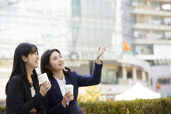 拿着咖啡聊天的年轻女性图片