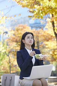 公园长凳上吃沙拉的女青年图片