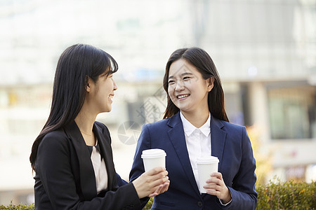 户外拿着咖啡相视微笑的商务女性图片