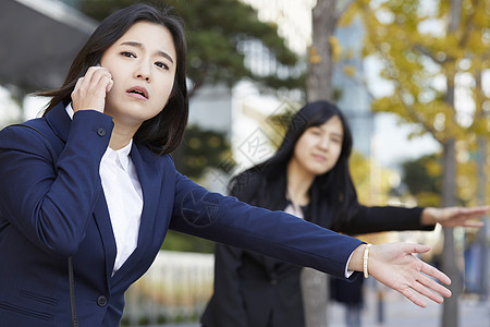 年轻女子站在路边焦急的拦车背景图片