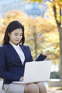 户外使用笔记本电脑的青年女子图片