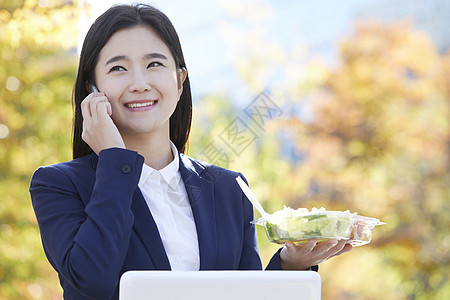 拿着沙拉打电话的年轻女子图片