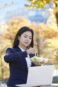 户外吃着沙拉的女青年图片