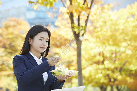 户外吃着沙拉的女青年图片