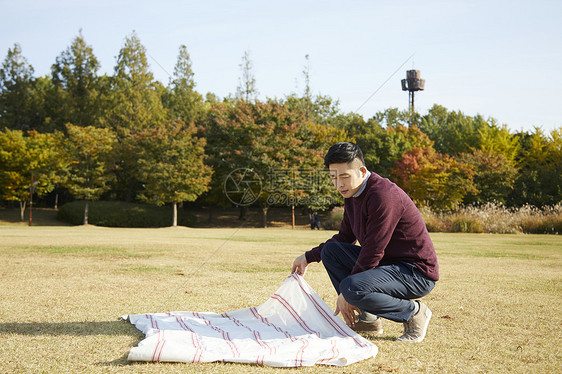 男人在草地上铺野餐垫图片