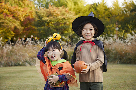 两个小南瓜户外草地上万圣节装扮的两个小孩开心玩耍背景