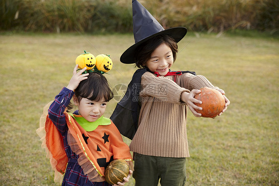 户外草地上万圣节装扮的两个小孩开心玩耍图片