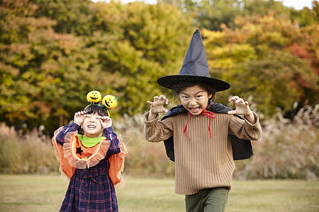 户外草地上万圣节装扮的两个小孩开心玩耍图片