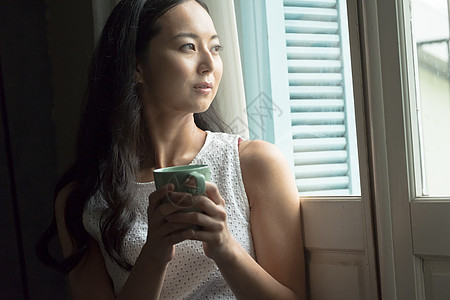 一个女人在窗口喝茶图片