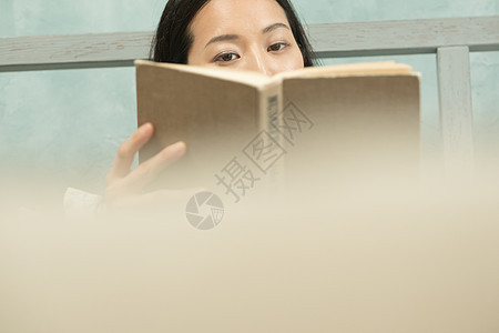 一个女人坐在床上读书图片
