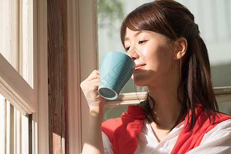 站在窗户旁喝水的女孩图片