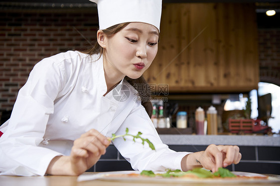 年轻女烘培师在点缀绿叶图片