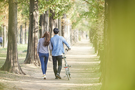 公园里郊游推着自行车的情侣背影图片