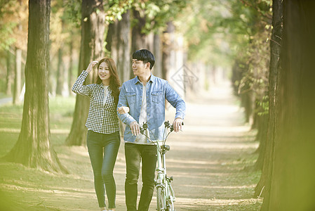 公园里郊游推着自行车的年轻情侣图片