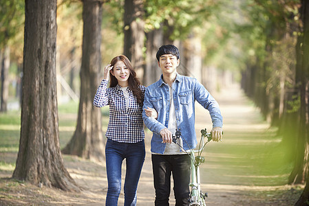 公园里散步推着自行车的年轻情侣图片