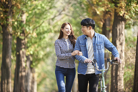 推着自行车散步的年轻情侣图片