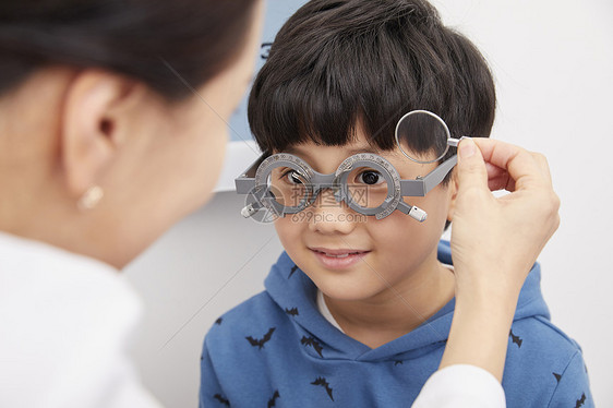 女医生为小男孩配戴近视眼镜图片