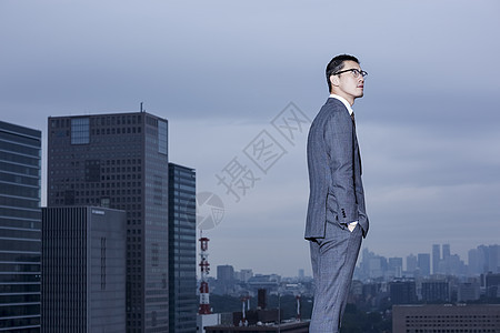 仰视亚洲人眼镜站立在屋顶的商人图片