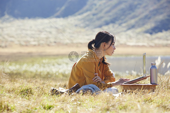 流浪盘腿商务女在草地上工作的女人图片